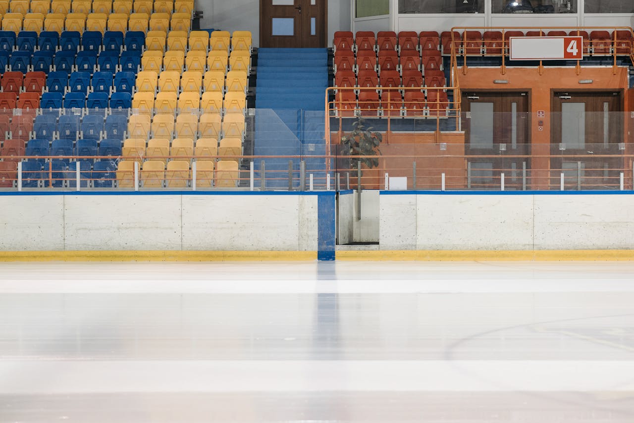 home-hero-bg Empty ice rink showcasing colorful bleachers with a modern sports venue design.