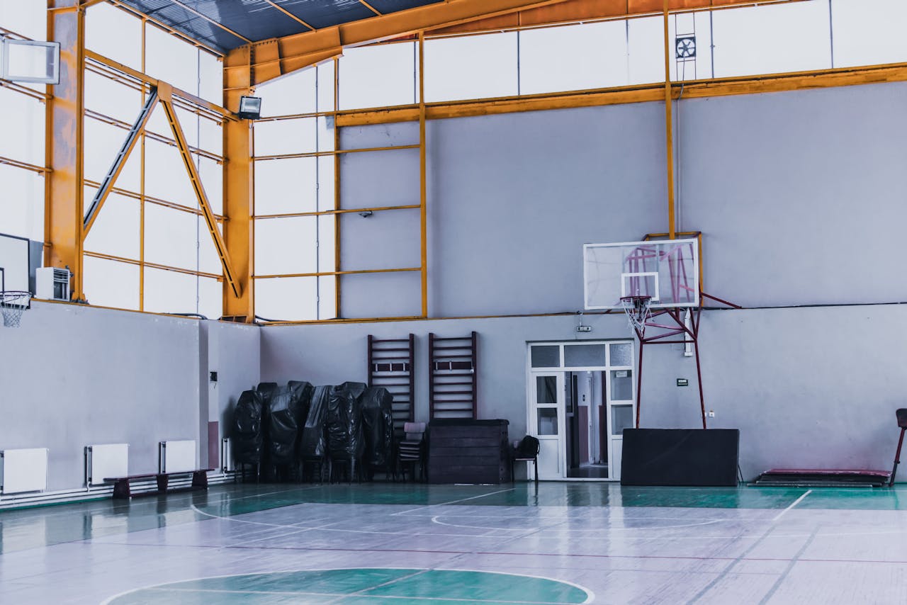 home-services-03 Modern empty sports hall with basketball hoop and various fitness equipment in daytime